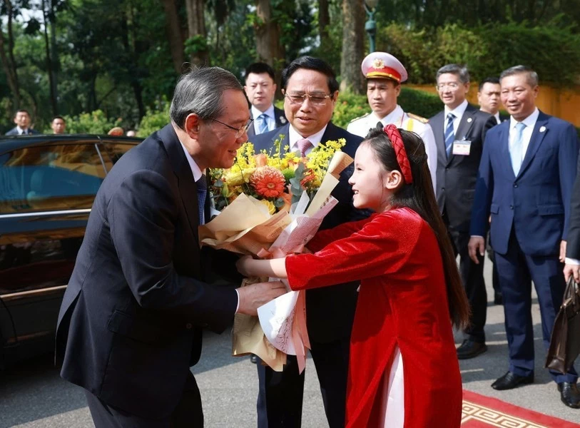 A Hanoi girl presents flowers to welcome Premier Li Qiang on his official visit to Vietnam. (Photo: VNA)