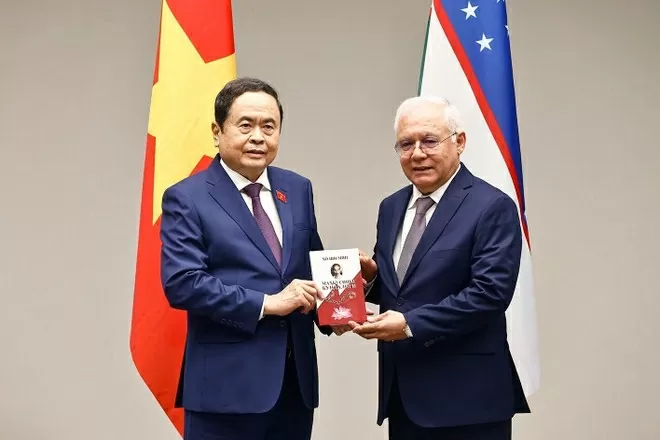 A member of the Committee on Interethnic Relations and Friendly Ties with Foreign Countries presents the book about Uncle Ho to NA Chairman Tran Thanh Man. (Photo: VNA)