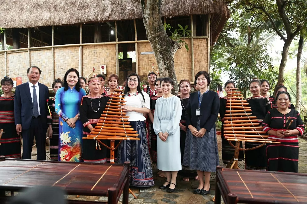 Phu nhân Lê Thị Bích Trân và Phu nhân Ishiba Yoshiko đến Làng dân tộc Xơ Đăng. Hai Phu nhân tiến vào làng trong sự vui mừng chào đón của bà con và gặp gỡ nghệ nhân ưu tú Y'Sinh, người chế tác nhạc cụ từ tre nứa.
