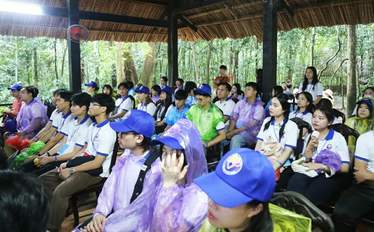 Các kiều bào trẻ chăm chú lắng nghe hướng dẫn viên giới thiệu về di tích lịch sử Địa đạo Củ Chi. (Ảnh: Thành Long)
