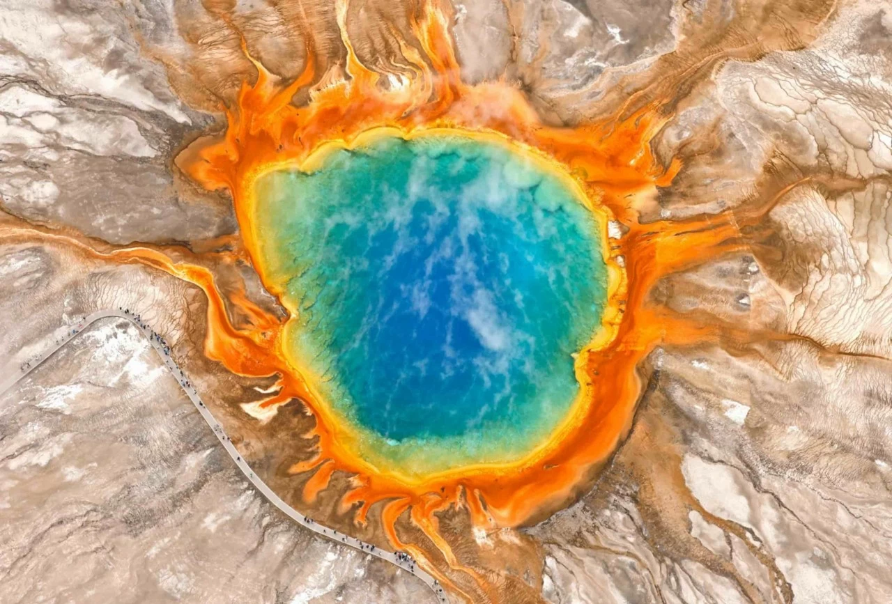 Bức ảnh chụp từ trên cao ngày Chủ nhật, 24/5, cho thấy du khách tham quan khu vực Grand Prismatic Spring nằm trong Yellowstone National Park. Đây là suối nước nóng lớn nhất nước Mỹ. Những dải màu rực rỡ bao quanh phần trung tâm màu xanh của suối được tạo nên bởi các vi sinh vật ưa nhiệt (thermophiles) — những sinh vật cực nhỏ phát triển mạnh trong môi trường nhiệt độ cao và xuất hiện phổ biến tại nhiều suối nước nóng ở Yellowstone. (Nguồn: Getty Images)