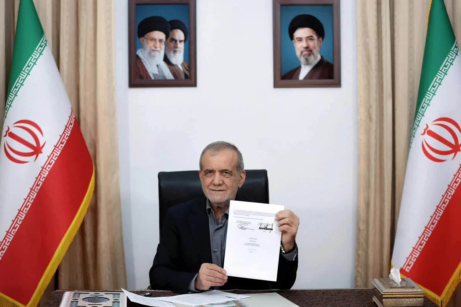 Tổng thống Iran Masoud Pezeshkian giơ bản thỏa thuận với Mỹ sau khi ký tại Tehran, Iran, ngày 18/6. Sau lễ ký, ông Pezeshkian viết trên mạng xã hội X: “Đây là một văn kiện mang tính lịch sử và là thông điệp từ một nước Iran hùng mạnh: hòa bình sẽ chỉ đạt được trên cơ sở tôn trọng lẫn nhau.” (Nguồn: WANA)