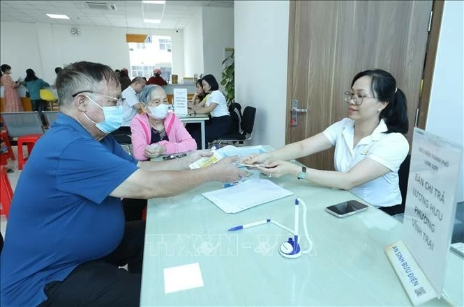 Cán bộ nhân viên Bưu điện chi trả lương hưu cho người dân. (Nguồn: TTXVN) Cán bộ nhân viên Bưu điện chi trả lương hưu cho người dân. (Nguồn: TTXVN)