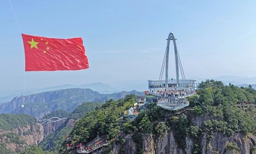Du khách hát bài ca yêu nước “Ode to the Motherland” dưới lá cờ quốc gia khổng lồ của Trung Quốc tại Khu thắng cảnh Thần Tiên Cư, huyện Tiên Cư, thành phố Đài Châu, tỉnh Chiết Giang, miền Đông Trung Quốc, ngày 27/9/2026, nhân kỷ niệm 77 năm Quốc khánh nước Cộng hòa Nhân dân Trung Hoa. Ảnh: VCG