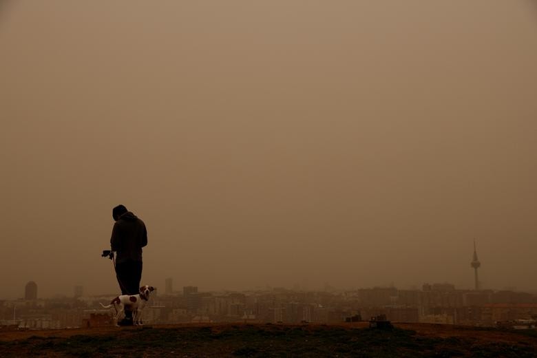 Một người đàn ông và một con chó đứng trên đồi khi cơn bão Celia thổi cát từ sa mạc Sahara qua Madrid, ngày 15 tháng 3. REUTERS / Susana Vera