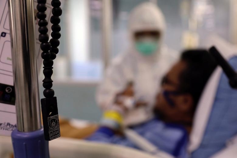 Chuỗi hạt cầu nguyện của người Hồi giáo treo lên khi một nhân viên chăm sóc sức khỏe điều trị cho một người đàn ông 53 tuổi bị bệnh coronavirus bên trong khu ICU cho bệnh nhân COVID-19 tại một bệnh viện do chính phủ điều hành ở Jakarta, Indonesia, ngày 29