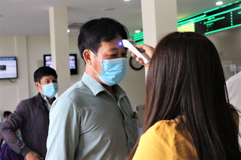 Checking temperature for a shopper at a wet market (Photo: VNA)