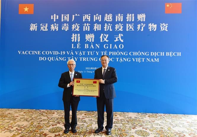 Đại sứ Việt Nam tại Trung Quốc Phạm Sao Mai (bên trái) thay mặt các địa phương Việt Nam tiếp nhận số hàng viện trợ từ Phó Chủ tịch Chính quyền Khu tự trị Dân tộc Choang Quảng Tây Hoàng Tuấn Hoa. Ảnh: Mạnh Cường - PV TTXVN tại Trung Quốc
