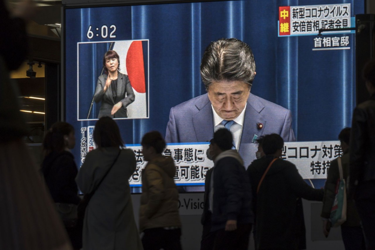 Người dân ở Osaka, Nhật Bản, đi ngang qua màn hình chiếu trực tiếp cảnh Abe nói về đại dịch Covid-19 vào năm 2020.Hình ảnh Tomohiro Ohsumi / Getty