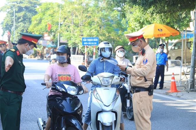 Lực lượng chức năng kiểm tra giấy đi đường của người dân tại chốt số 14 cầu Thạch Bích trên QL 21B, thuộc địa bàn xã Bích Hoà, huyện Thanh Oai. (Nguồn: TTXVN)