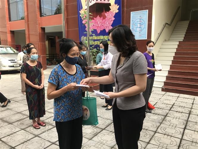 Chủ tịch Hội Liên hiệp phụ nữ thành phố Hà Nội Lê Kim Anh trao suất quà cho nữ lao động di cư gặp khó khăn, ngày 18/9/2021. (Nguồn: TTXVN)