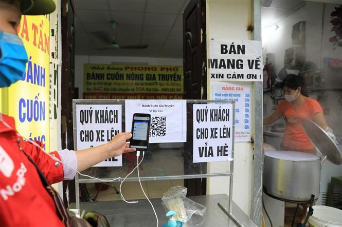 Tại một cửa hàng bán bánh cuốn trên phố Đội Cấn, các shipper đến lấy hàng phải quét mã QR-code để khai báo y tế rồi mới được lấy hàng. (Nguồn: TTXVN) Tại một cửa hàng bán bánh cuốn trên phố Đội Cấn, các shipper đến lấy hàng phải quét mã QR-code để khai báo y tế rồi mới được lấy hàng. (Nguồn: TTXVN)