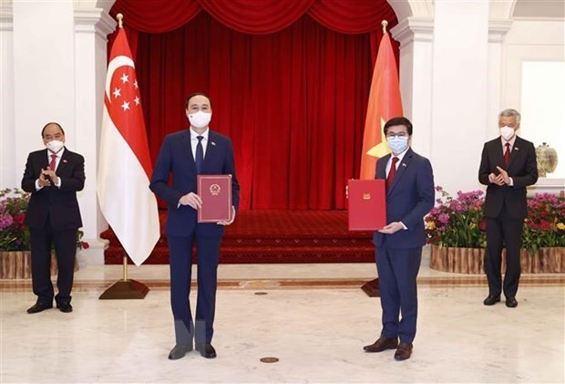 Vietnamese President Nguyen Xuan Phuc (first, left) and Singaporean Prime Minister Lee Hsien Loong (first, right) witness the exchange of a newly signed MoU between the Viet Nam Fatherland Front and the People’s Association of Singapore on February 25. (Photo: VNA)