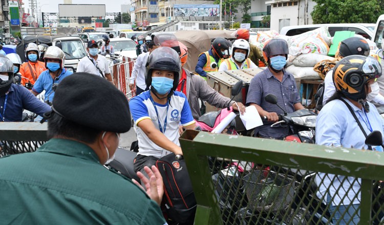 Nhiều người đi xe máy thuyết phục cảnh sát cho phép đi qua rào chắn. (Nguồn: Khmer Times)