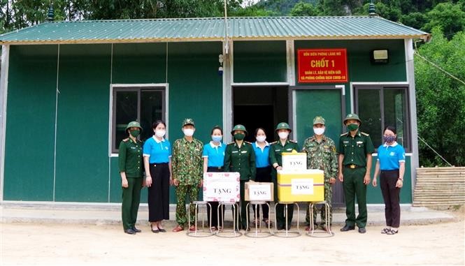 Các cán bộ Đồn Biên phòng Làng Mô trực tại chốt kiểm soát dịch tiếp nhận các phần quà ý nghĩa do những nữ đồng đội trao tặng. (Nguồn: TTXVN)