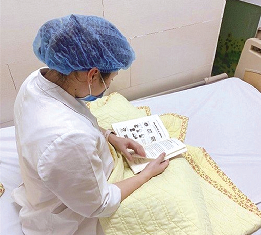 Nữ điều dưỡng của Viện Tim mạch (khu C Bệnh viện Bạch Mai) tranh thủ đọc sách vào buổi tối tại khu cách ly. (Nguồn: Bộ Y tế)