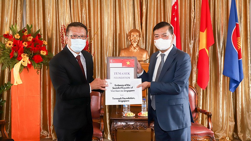 Đại sứ Mai Phước Dũng (phải) tiếp nhấn tượng trưng lô hàng do Quỹ Tamasek trao tặng. Ảnh: (Nguồn: TTXVN)