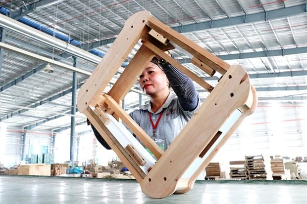 A worker checks wooden products before packaging for export in a wood processing company in Binh Duong province. (Photo: VNA)