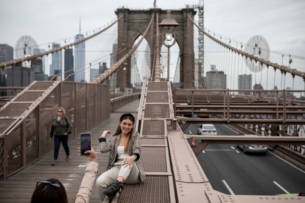 A visitor from Mexico took photos on the Brooklyn Bridge. The number of tourists to New York City plunged to 22 million last year from 66 million in 2019.Credit...Kirsten Luce for The New York Times