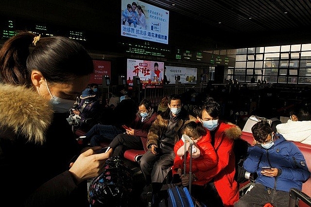 Người dân xem điện thoại thông minh khi ngồi chờ tàu ở Bắc Kinh hôm 27/1 (Ảnh: Reuters)