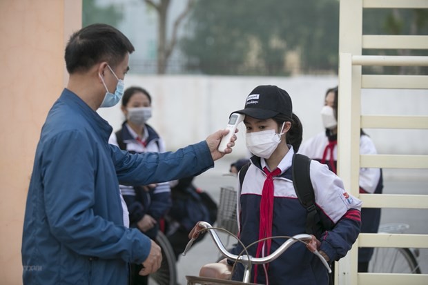 Đo thân nhiệt cho học sinh trước khi vào lớp học. (Ảnh: TTXVN)