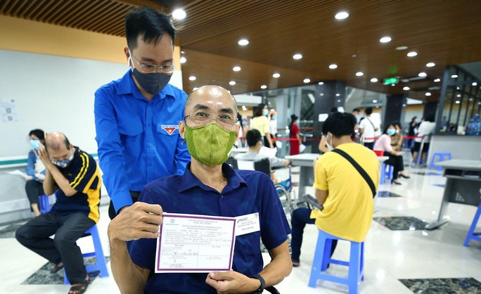 Một người khuyết tật nhận giấy chứng nhận sau khi tiêm mũi 1 vắc-xin Covid-19