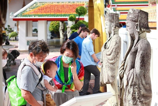 Một cặp vợ chồng người Hàn Quốc đọc hướng dẫn và nghi thức đi chùa tại Wat Phra Chetuphon Wimon Mangkhalaram (Wat Pho) hoặc 'Chùa Phật Nằm' ở quận Phra Nakhon hôm thứ Sáu. Đây là ngày đầu tiên Thái Lan mở cửa trở lại hoàn toàn cho khách du lịch nước ngoài. (Ảnh: Apichart Jinakul)