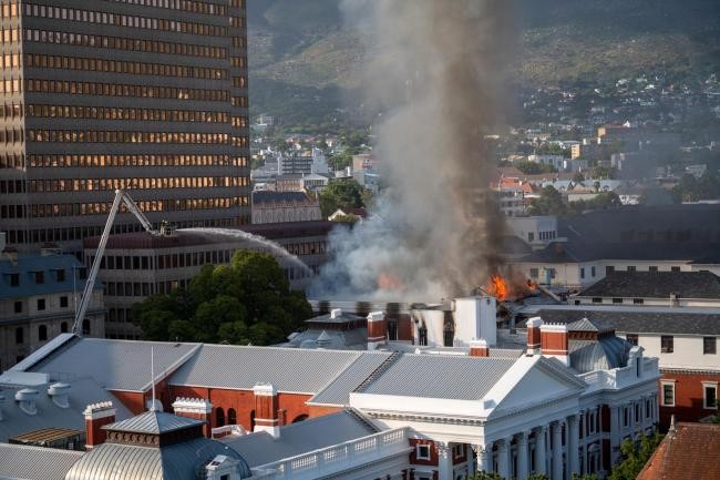 Lính cứu hỏa phun nước vào ngọn lửa bùng lên từ một tòa nhà tại Quốc hội Nam Phi. (Nguồn: Wiltshiretimes)