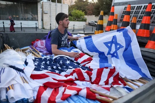 (07.13) Một người dân chuẩn bị quốc kỳ của hai nước Mỹ và Israel trước thềm chuyến thăm của ông Joe Biden. (Nguồn: AFP/Getty Images)