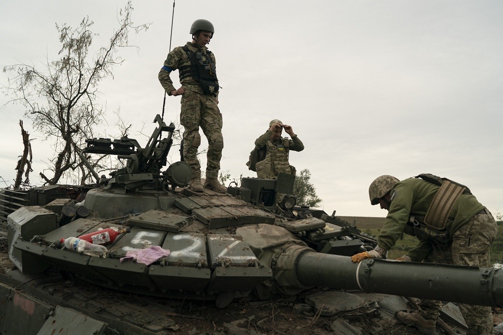 (09.19) Các binh sỹ Ukraine kiểm tra một chiếc xe tăng Nga bị phá hủy tại khu vực Kharkov ngày 17/9. (Nguồn: AP)