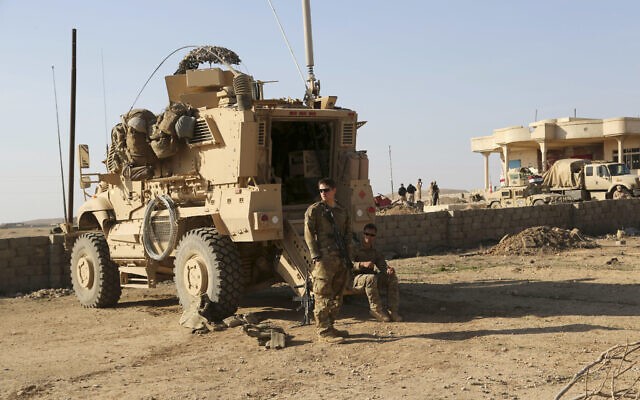  Các binh sĩ Quân đội Mỹ đứng bên ngoài xe bọc thép của họ trong một căn cứ quân sự. (Nguồn: AFP)