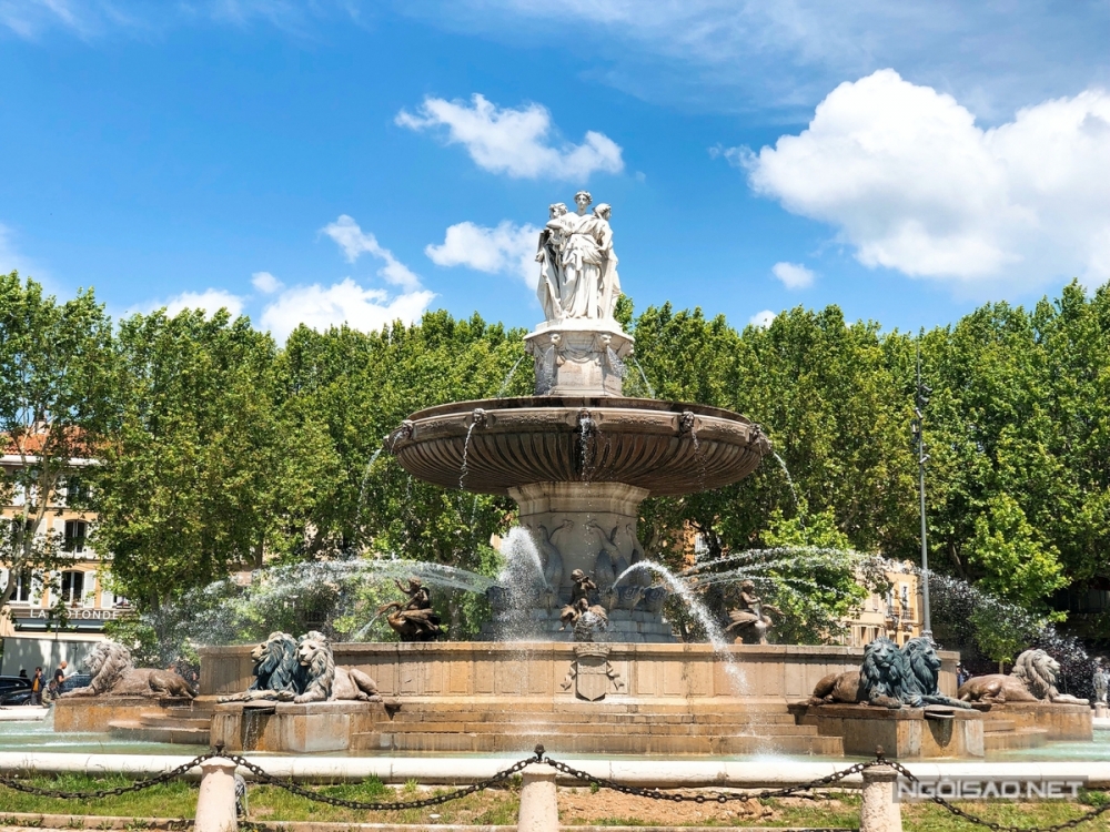 Aix-en-Provence vốn không phải là một địa điểm du lịch ưa chuộng với người Việt Nam. Song nếu muốn rời xa thủ đô Paris hoa lệ, tìm kiếm sự yên bình và khám phá đời sống người dân địa phương, Aix-en-Provence trở thành địa điểm đáng cân nhắc cho bạn. Nơi đây cách Paris khoảng 760 km về phía Nam. Từ thủ đô, bạn có thể đi tàu tốc hành TGV (ba tiếng đồng hồ) hoặc xe bus chạy đêm khoảng 11 tiếng đồng hồ. Nếu chọn phương án đi bus đêm, Aix-en-Provence sẽ đón bạn bằng ánh bình mình trong trẻo, hàng cây xanh mát cùng đài phun nước La Rotonde - biểu tượng quan trọng của thành phố.