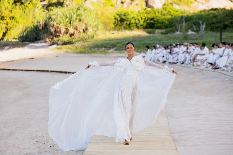 Hoa hậu H'Hen Niê sải bước catwalk trong vai trò vedette show Đỗ Mạnh Cường trên sàn diễn dài 380m được dựng từ gỗ, nằm trong khuôn viên bãi biển thuộc một resort 6 sao tại Ninh Thuận.
