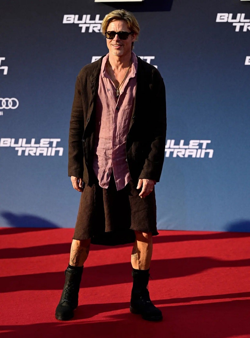 Brad Pitt khác lạ trong chiếc váy nâu đồng điệu với áo khoác. Nam diễn viên 58 tuổi kết hợp cùng áo sơ mi bỏ ngỏ cúc và đôi bốt cổ cao, tạo diện mạo phá cách nhưng vẫn toát lên vẻ nam tính.