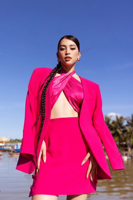 Hoa hậu Tiểu Vy nổi bật trên phố cổ Hội An với bộ trang phục kết hợp giữa khăn lụa, áo blazer và chân váy gam hồng fuchsia.