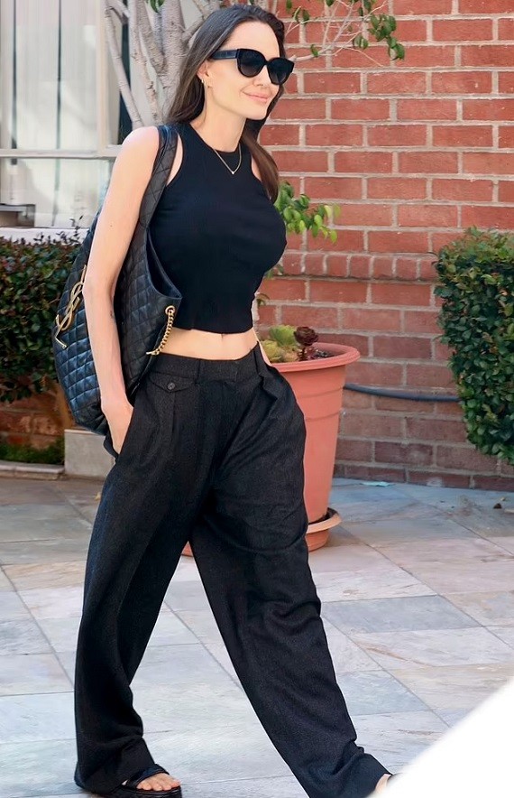 Angelina Jolie rời một tòa nhà ở Beverly Hills, Los Angeles hôm 24/8 trong bộ trang phục trẻ trung, phóng khoáng. Ngôi sao 'Maleficent' kết hợp với phụ kiện cá tính bao gồm khuyên tai, dây chuyền, kính râm, sandal đế bằng.