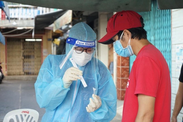 Nhân viên y tế hướng dẫn người dân tự làm test nhanh Covid-19 tại nhà. (Nguồn: Báo CAND)