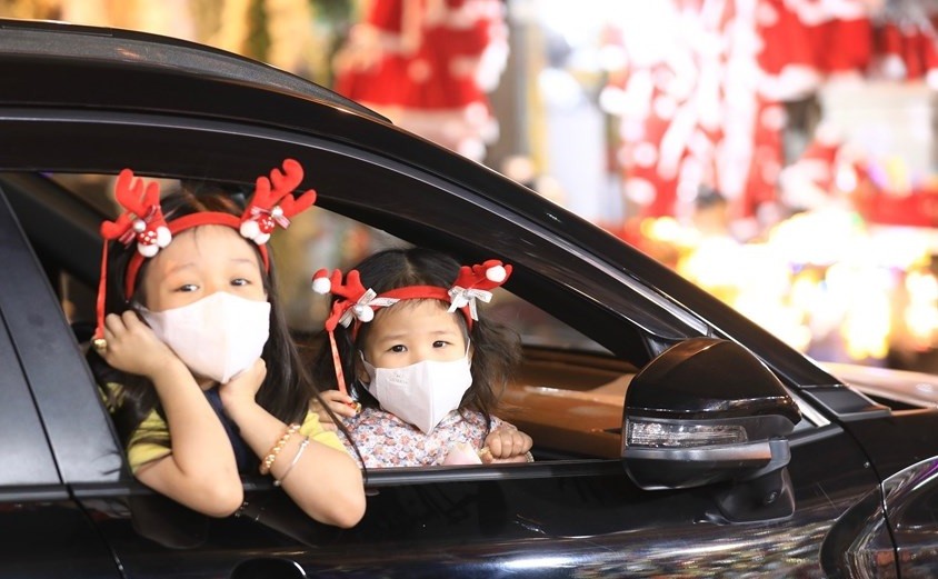 Các em bé Hà Nội được cha mẹ đeo khẩu trong phòng chống Covid-19 khi đi chơi Noel ngoài phố. (Nguồn: Dân trí)