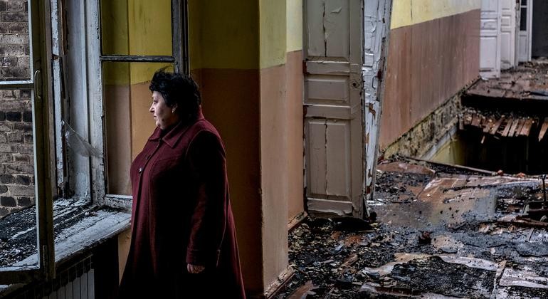 Người phụ nữ đứng trong một ngồi trưởng bị hư hại sau pháo kích tại  Krasnohorivka, Donetsk Oblast, Ukraine (Nguồn: UNICEF)