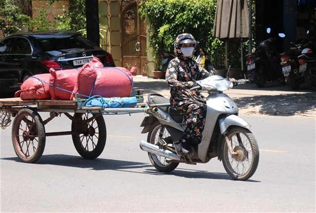 A motorbike driver in central Quảng Trị province covers herself from top to toe to avoid the scorching sun. (Photo: VNA)