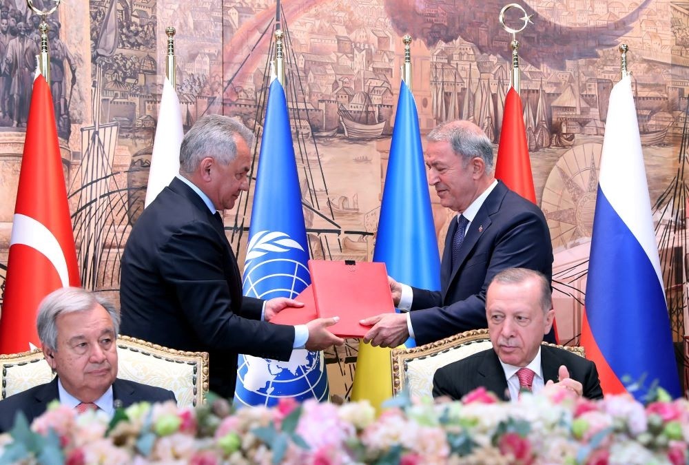 Bộ trưởng Quốc phòng Nga Sergei Shoigu đứng bên trái và Bộ trưởng Quốc phòng Thổ Nhĩ Kỳ Hulusi Akar trao đổi tài liệu tại lễ ký kết ở Istanbul ngày 22/7 với sự chứng kiến của Tổng thư ký Liên Hợp Quốc António Guterres ngồi bên trái và Tổng thống Thổ Nhĩ K