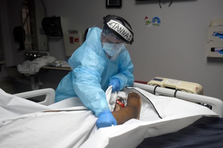 Tanna Ingraham đặt thi thể của một bệnh nhân tử vong do Covid-19 vào túi đựng thi thể, tại Trung tâm Y tế United Memorial ở Houston, Texas, Mỹ, ngày 30/12/2020. Tính đến tối 3/1, Mỹ ghi nhận… (Nguồn: Reuters)