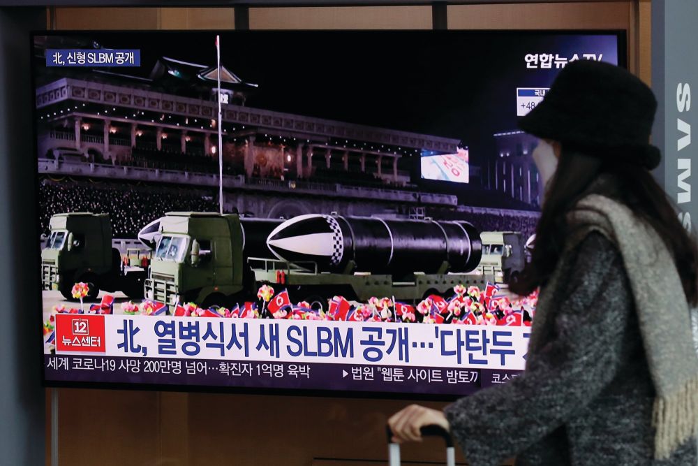 Một người phụ nữ đeo khẩu trang đi trước màn hình TV chiếu chương trình tin tức tường thuật về cuộc duyệt binh của Triều Tiên tại Ga Tàu Seoul ở Seoul, Hàn Quốc, hôm thứ Sáu. (Nguồn: AP)