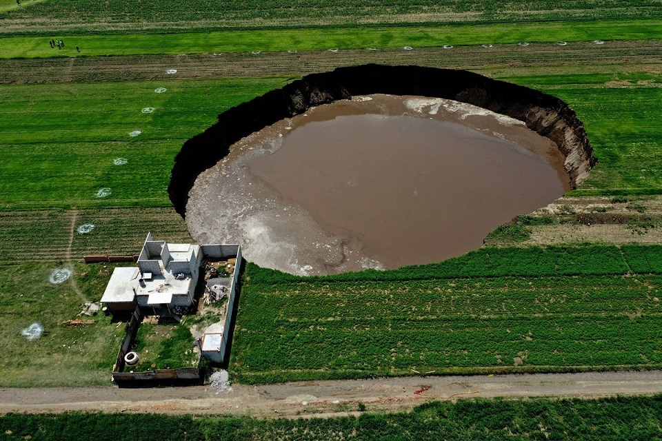 Bức ảnh chụp từ trên cao cho thấy một hố tử thần khổng lồ trên một cánh đồng ở Santa Maria Zacatepec, bang Puebla, Mexico, ngày 1/6.  Hố tử thần rộng tới 80 mét và tiếp tục có xu hướng lan rộng. Các nhà khoa học và các nhà chức trách đang xem xét các giả thuyết về nguyên nhân vụ việc, có thể là do một lỗi địa chất hoặc các biến đổi về hàm lượng nước trong đất. (Nguồn: Getty)