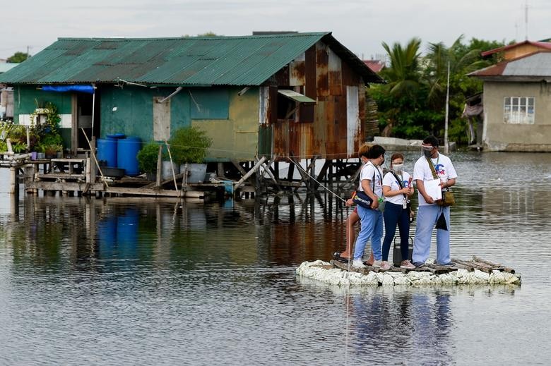 Nhân viên Nhân viên y tế đi trên chiếc bè tạm bợ trong chiến dịch đến từng nhà người dân để tiêm vaccine ngừa Covid-19 cho những công dân bị ốm phải nằm liệt giường ở thành phố Valenzuela, Metro Manila, Philippines, ngày 6/7. (Nguồn: Reuters)y tế băng qua