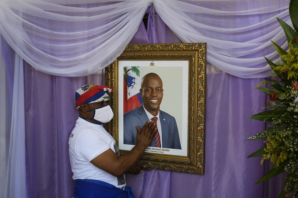 Người đàn ông chạm vào chân dung của cố Tổng thống Haiti Jovenel Moise bên ngoài một nhà thờ lớn ở Cap-Haitien, Haiti, nơi tổ chức lễ tưởng niệm, ngày 22/7. Ông Moise đã bị ám sát hồi đầu tháng tại nhà riêng bởi một nhóm sát thủ. (Nguồn: AP)