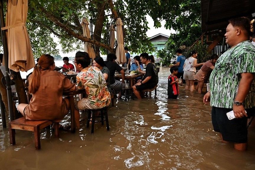 Thực khách ăn uống tại quán Chaopraya Antique Café ở Nonthaburi, phía Bắc Bangkok, Thái Lan trong khi nước lũ từ sông Chao Phraya tràn vào. (Nguồn: Getty)