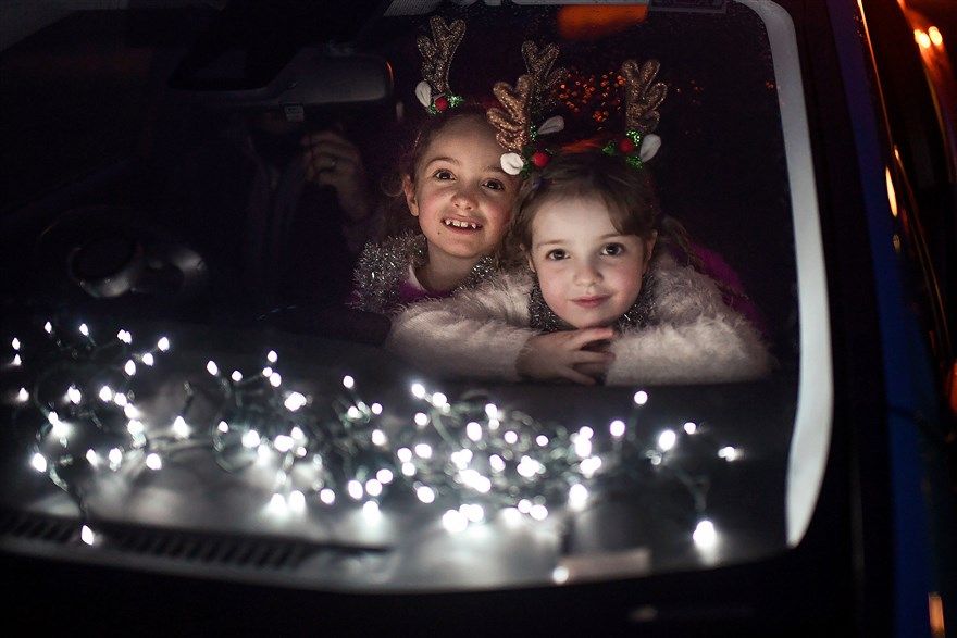 Hai bé gái nhìn ra cửa kính ô tô cùng cha mẹ tham dự buổi xem biểu diễn ngoài trời từ ô tô tại trường nữ sinh Kilgarston ở Perth, Scotland, ngày 10/12, trong bối cảnh giãn cách xã hội do dịch Covid-19. (Nguồn: Getty)