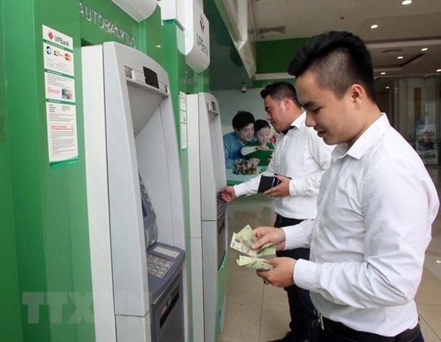 Office workers withdraw money from an ATM. (Photo: VNA)